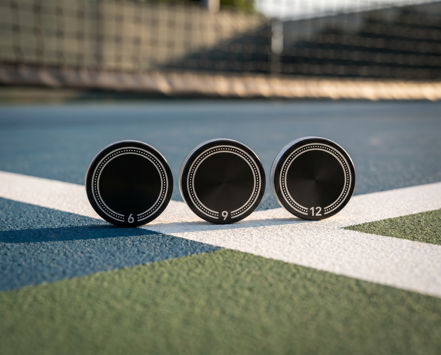 Anchor Cap weight coins standing on a pickleball court line